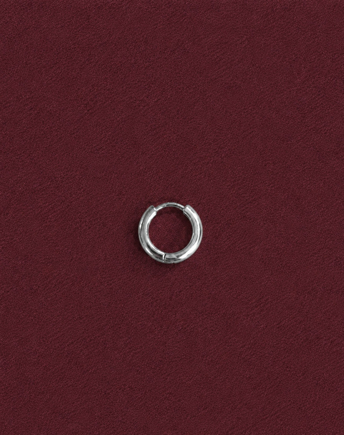 Single small silver hoop, set on burgundy suede