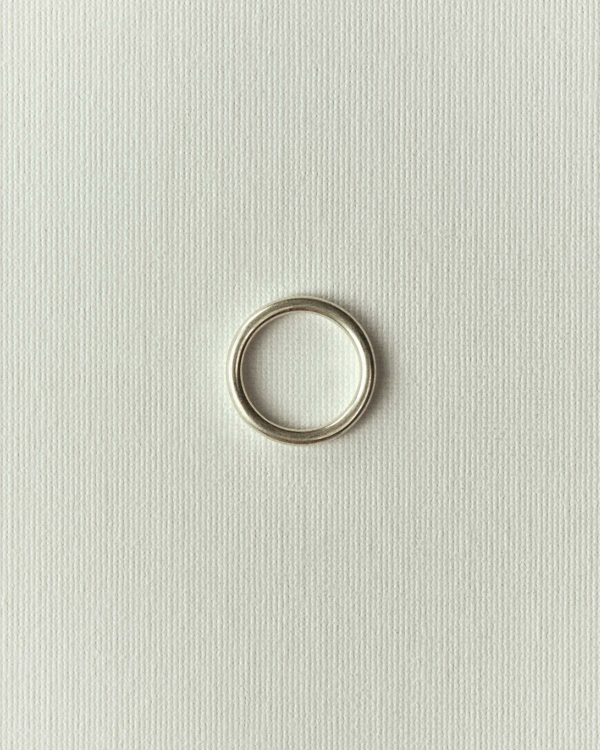 Plain silver band, flat on textured off-white paper