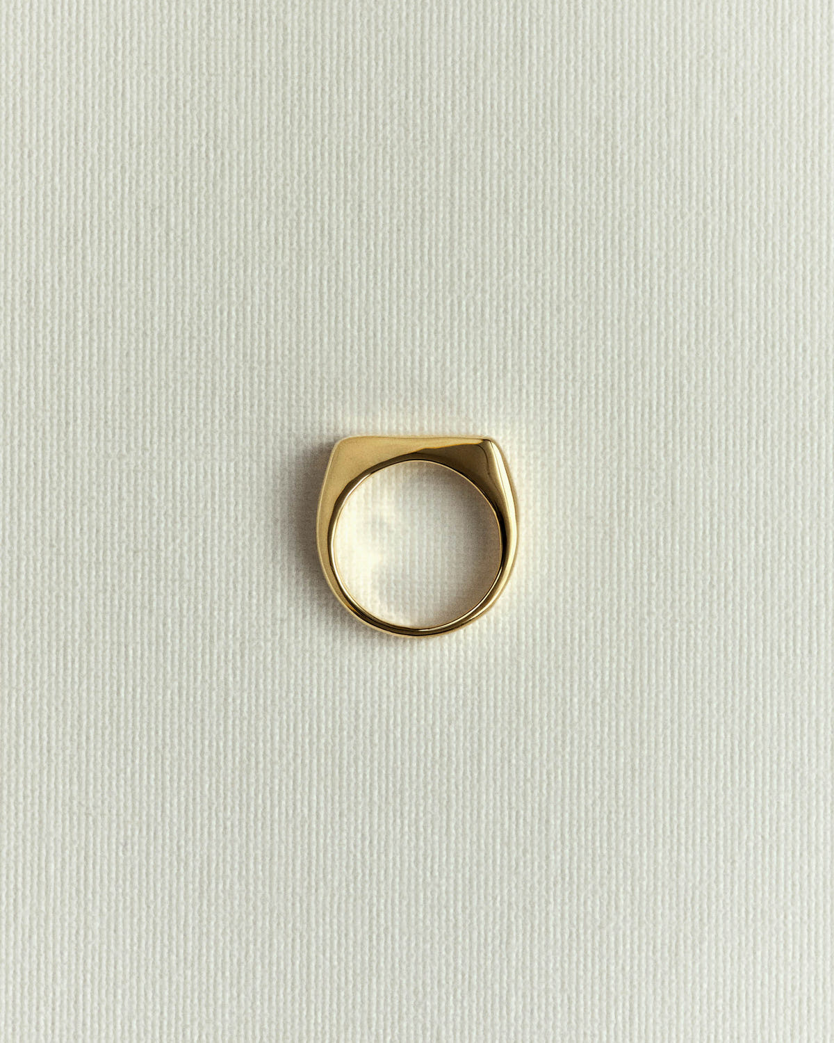 Gold version standing upright, flat top facing forward, on textured cream paper