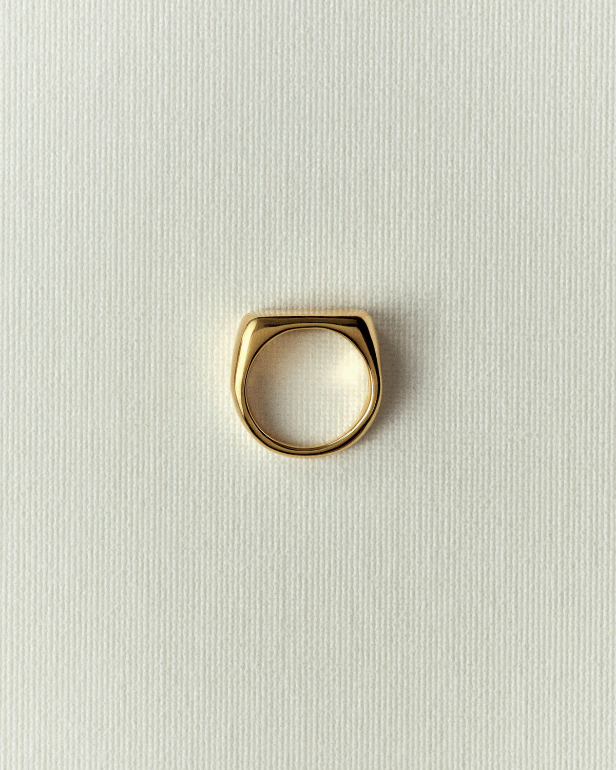 The same in polished gold, domed top with softened corners, upright on off-white paper