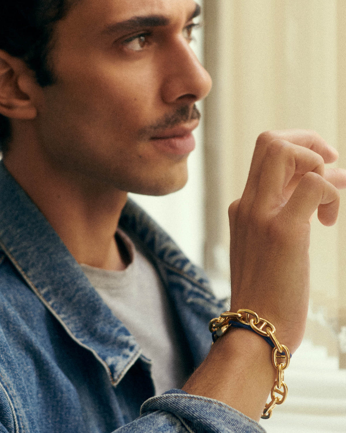 Worn at the wrist with a navy cord, denim jacket in soft light