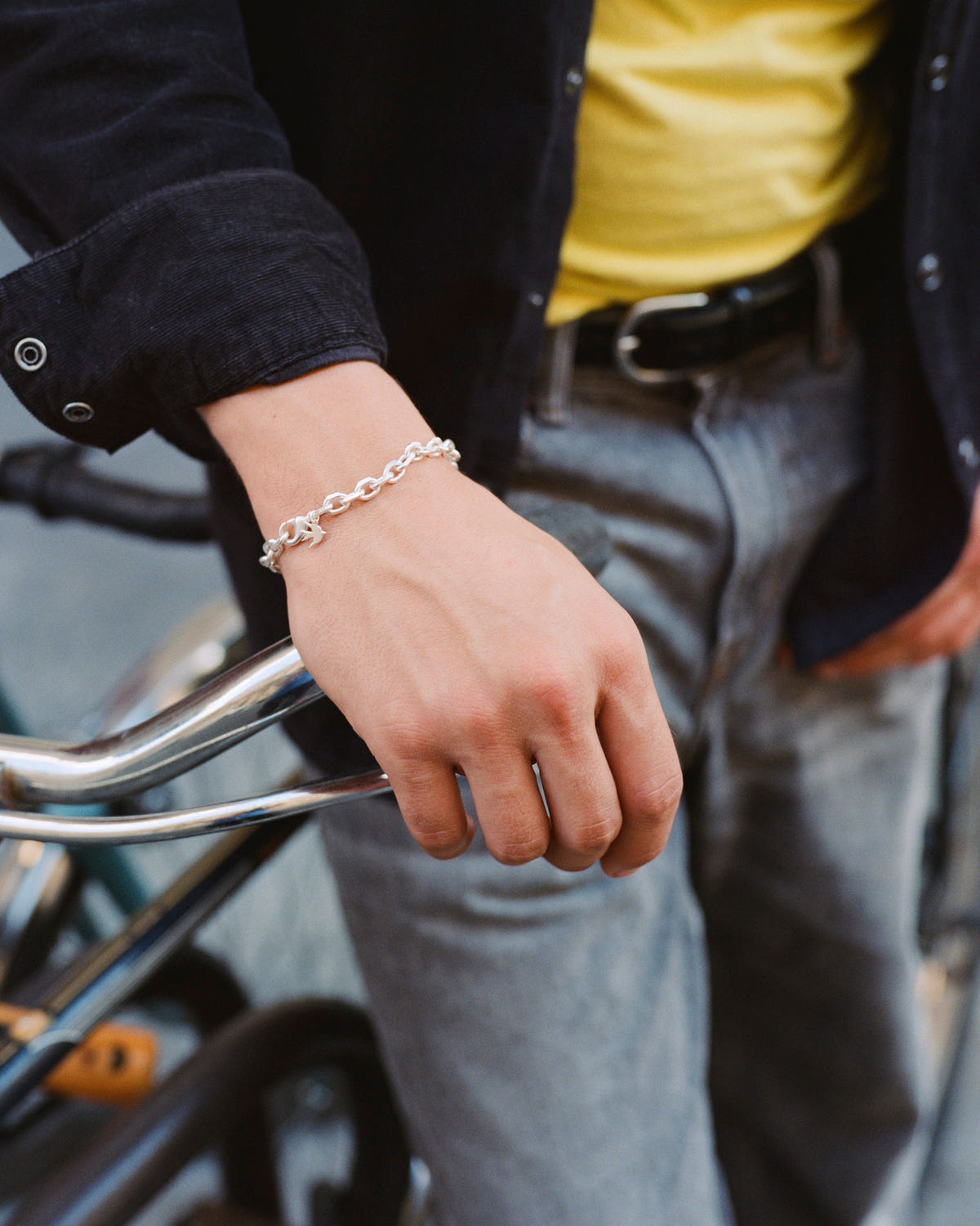 Silver-plated thin faceted trace chain bracelet on the wrist, hand on a bicycle handlebar