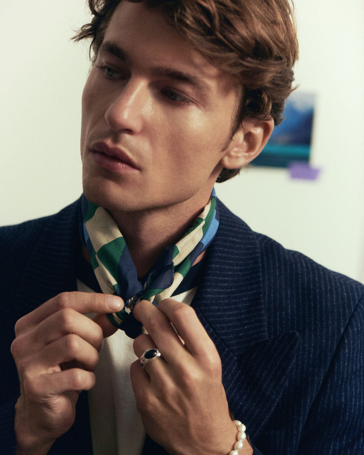 Hands adjusting the knot at the neck, green and blue checks over a navy jacket