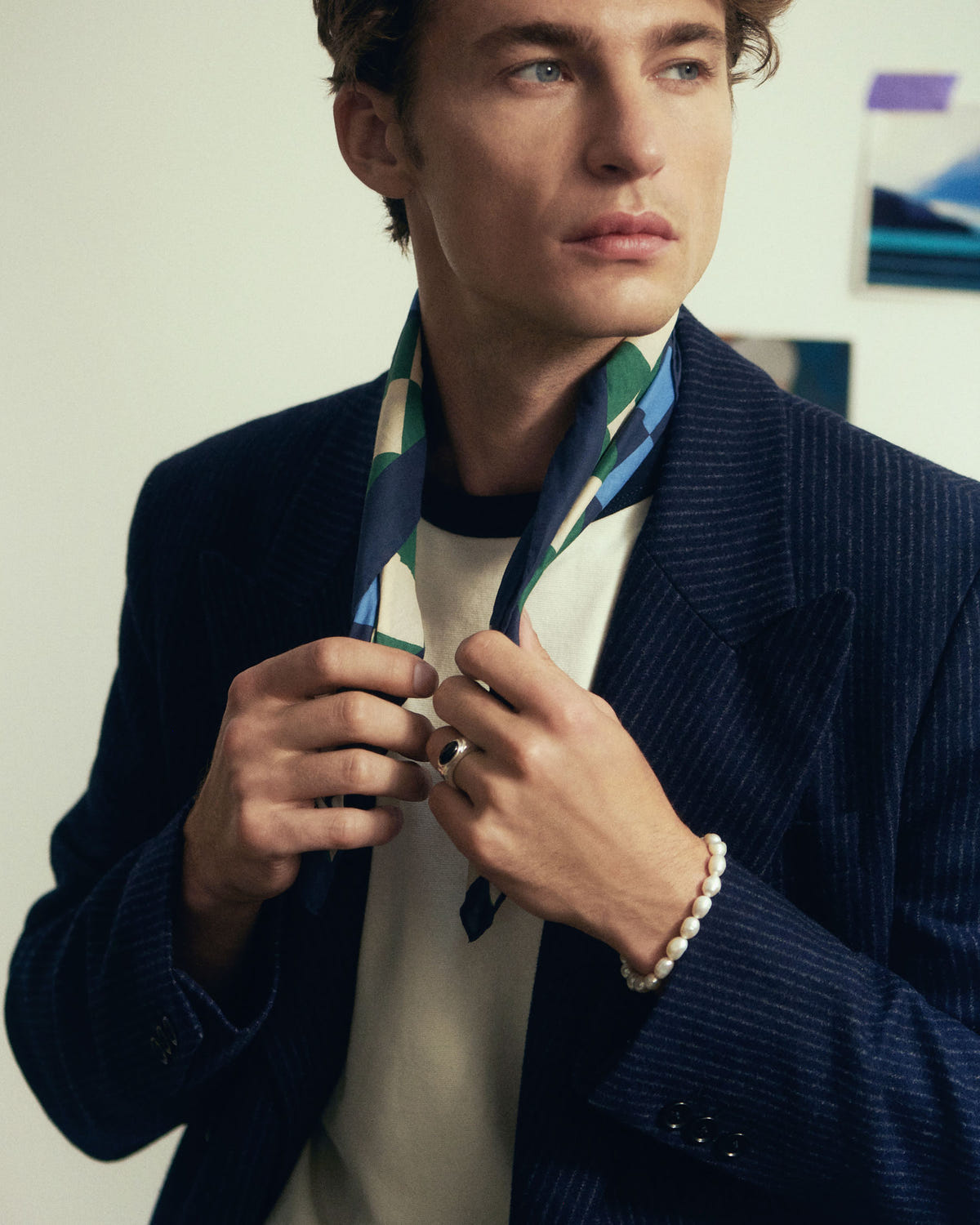 Both ends pulled forward over an off-white tee, navy pinstripe jacket