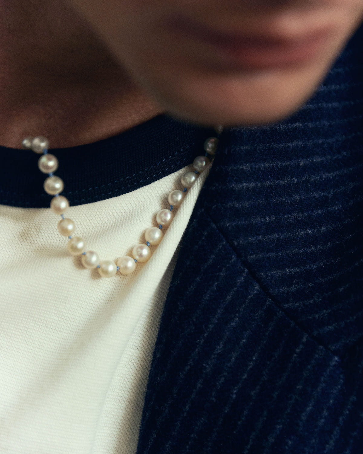 Close-up worn at the neck, over an off-white tee and ribbed navy knit