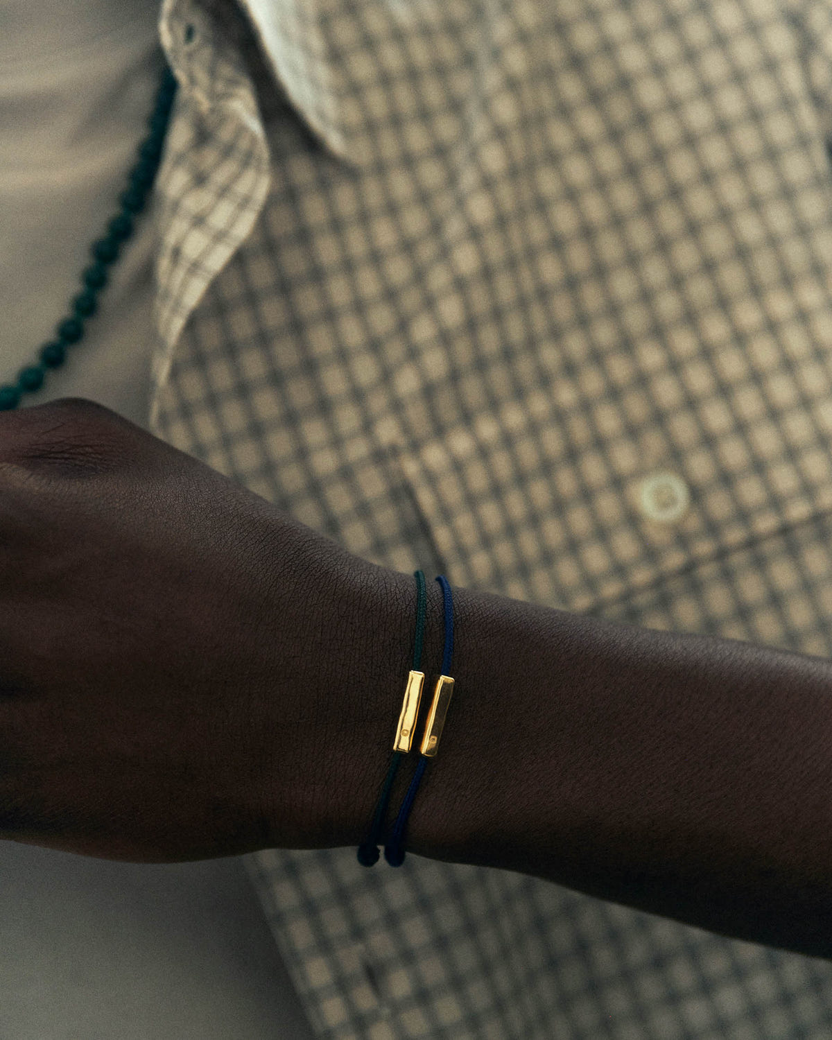 Two navy and dark green cords with gold elements, checked shirt in the background