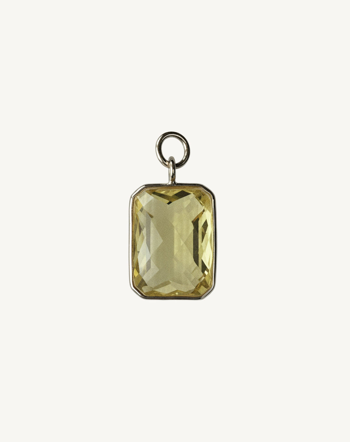 Large faceted pale yellow stone set in silver, big open jump ring, cream background