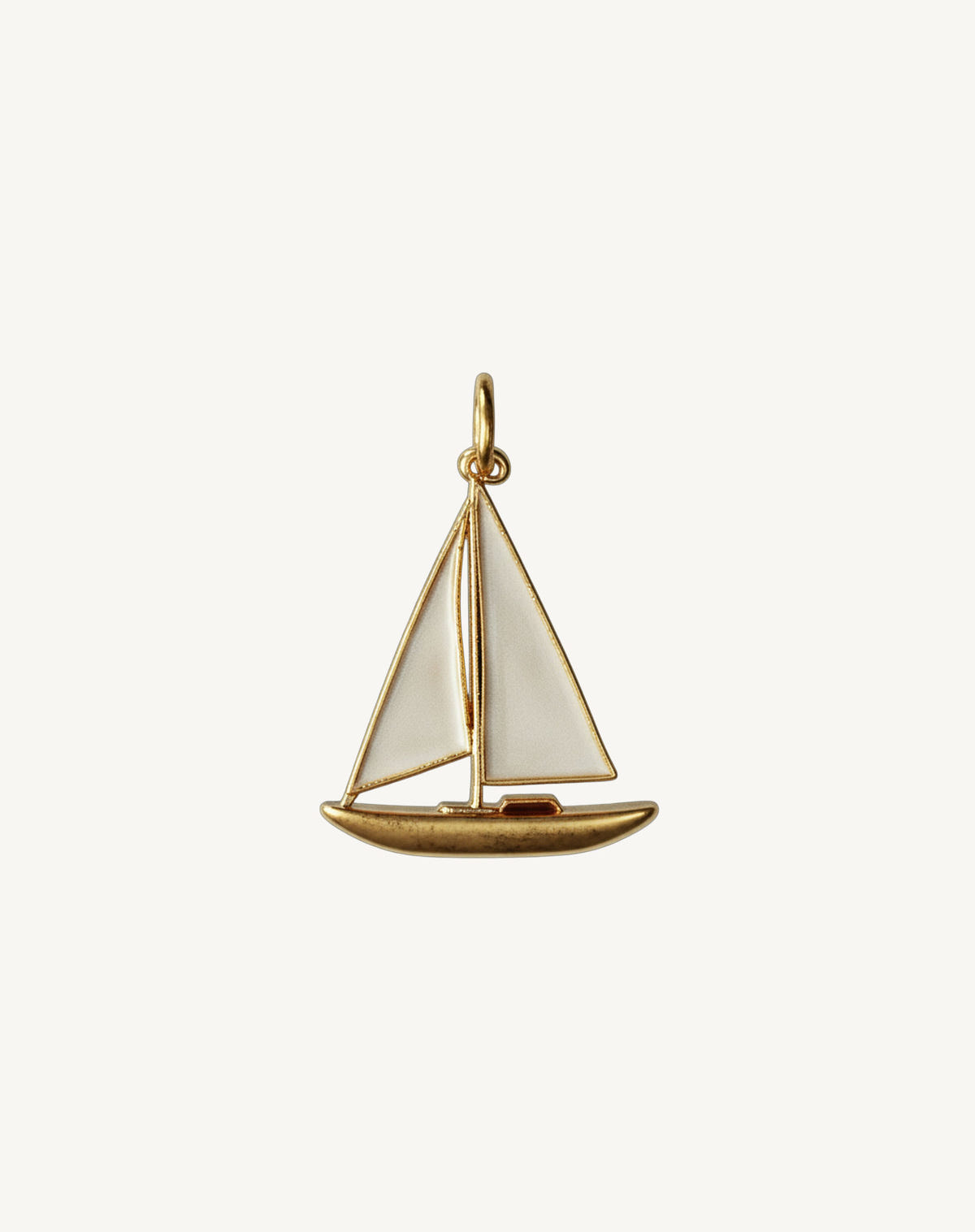 Gold sailboat with ivory enamel sails and a jump ring, cream background
