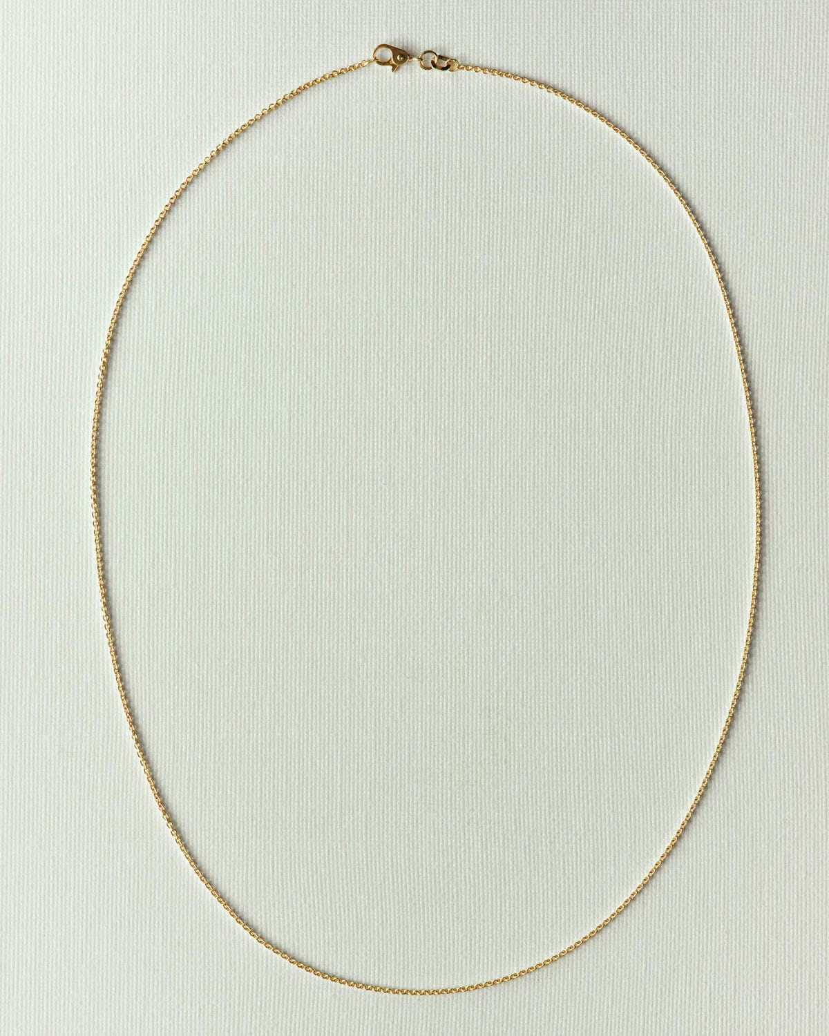 The same chain in gold, even oval loop on off-white paper