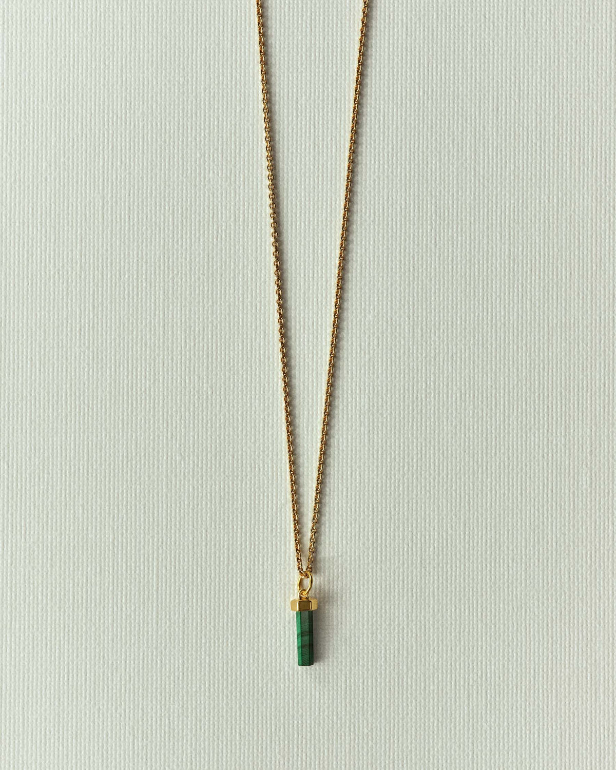 The same pendant in veined green stone, hanging from a fine gold chain