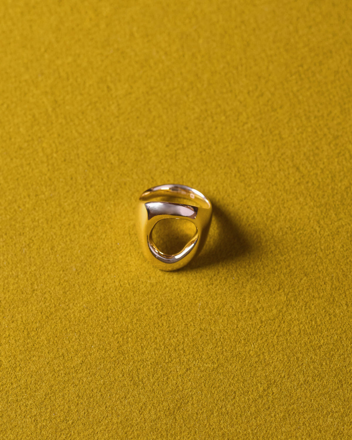 Chunky gold version standing on mustard felt, oval opening visible