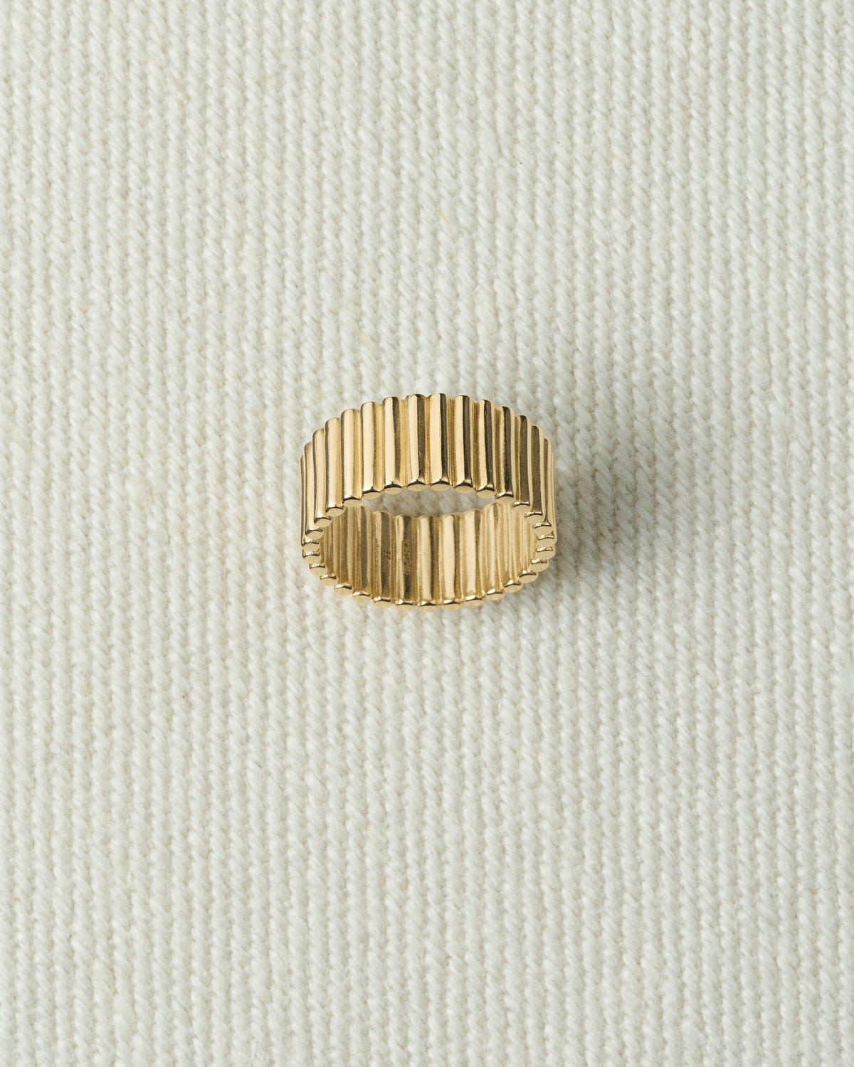 Wide gold ribbed band lying flat on textured ecru canvas