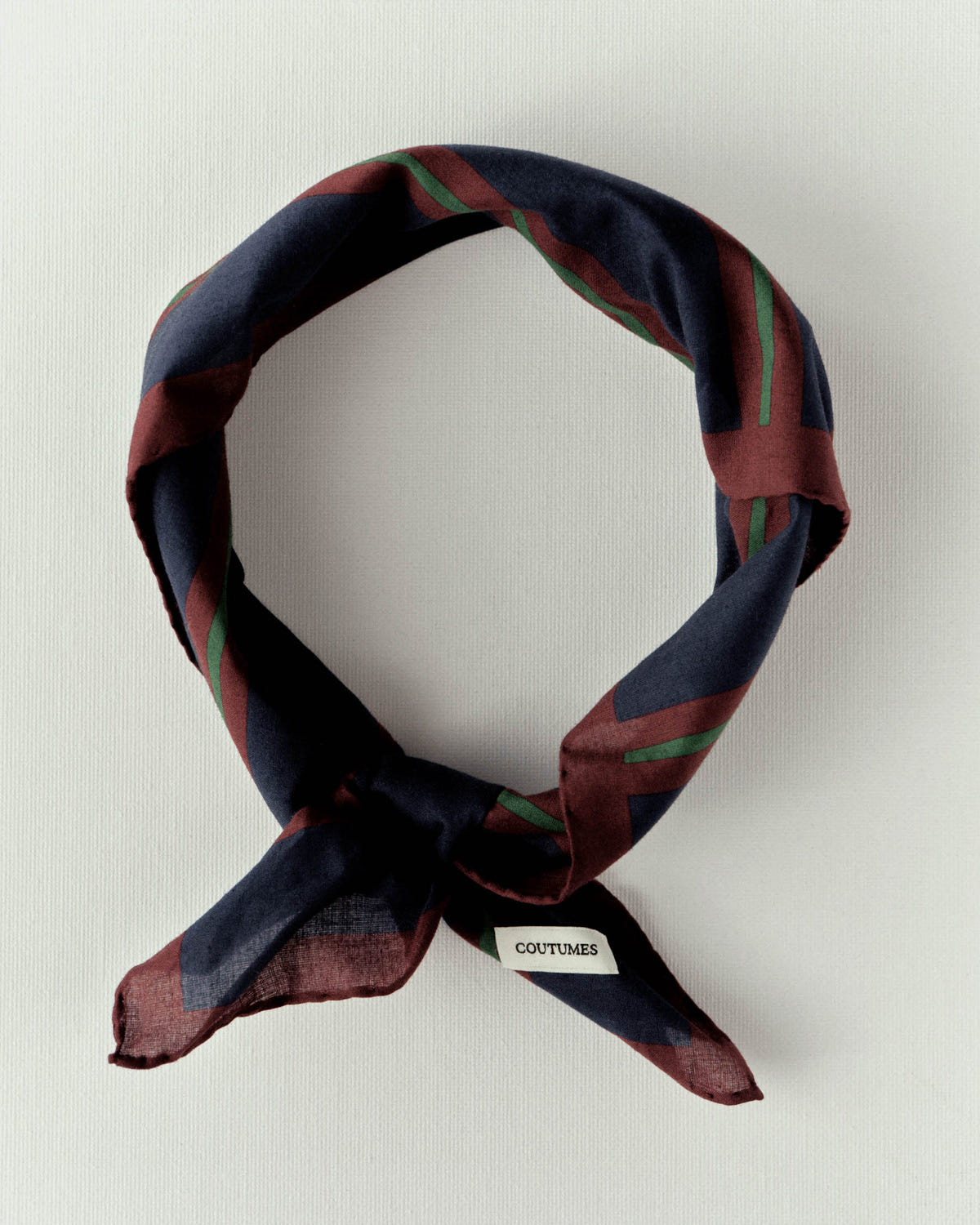 Foulard bleu marine à rayures bordeaux et vertes, roulé et noué en cercle